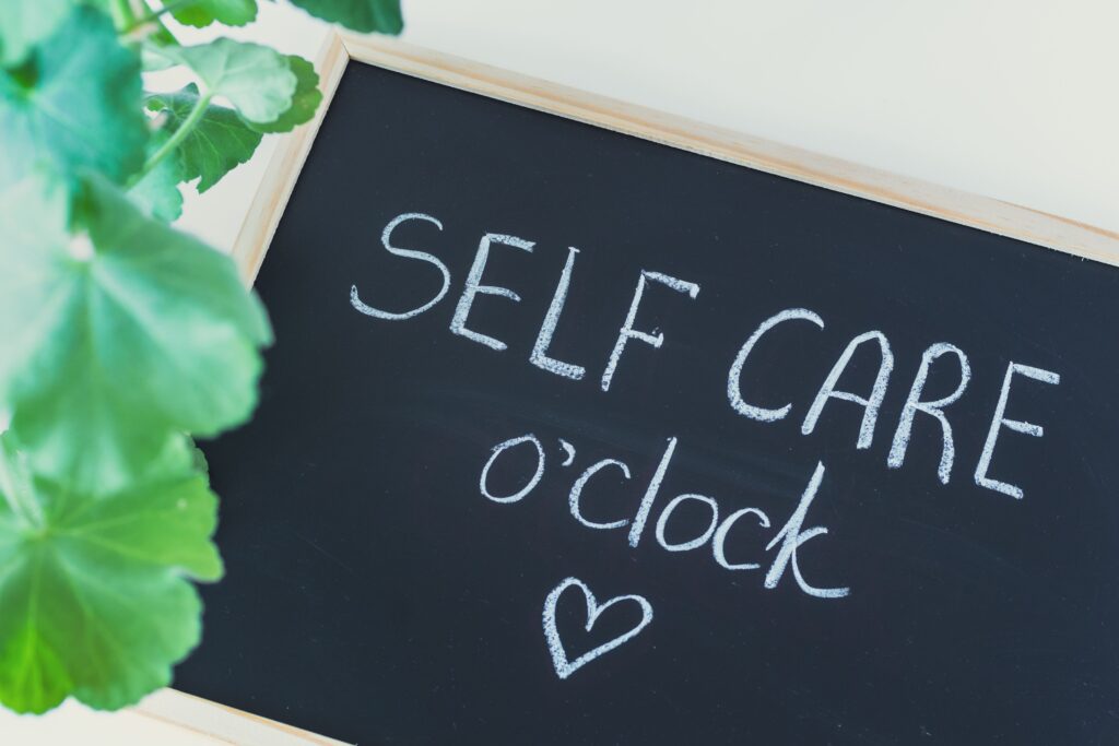 Chalkboard with the words self care o'clock and a heart on it, symbolizing our self-care workshops