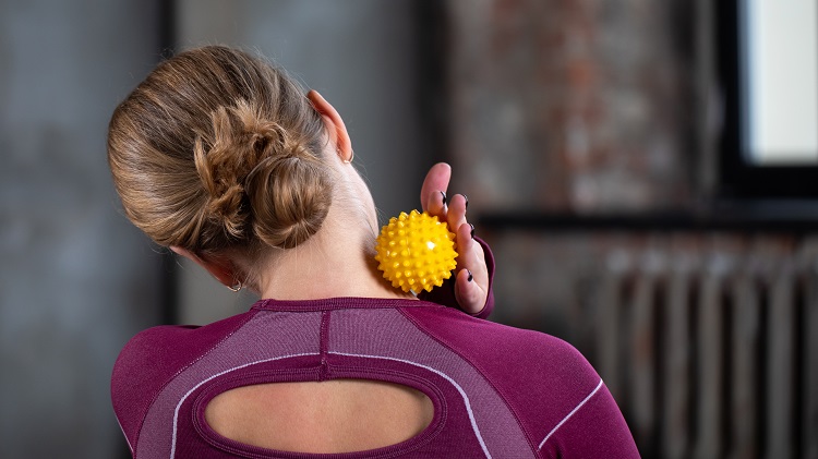 Woman using a yoga ball as you too can learn to do in our Self-care Workshop on Self-massage