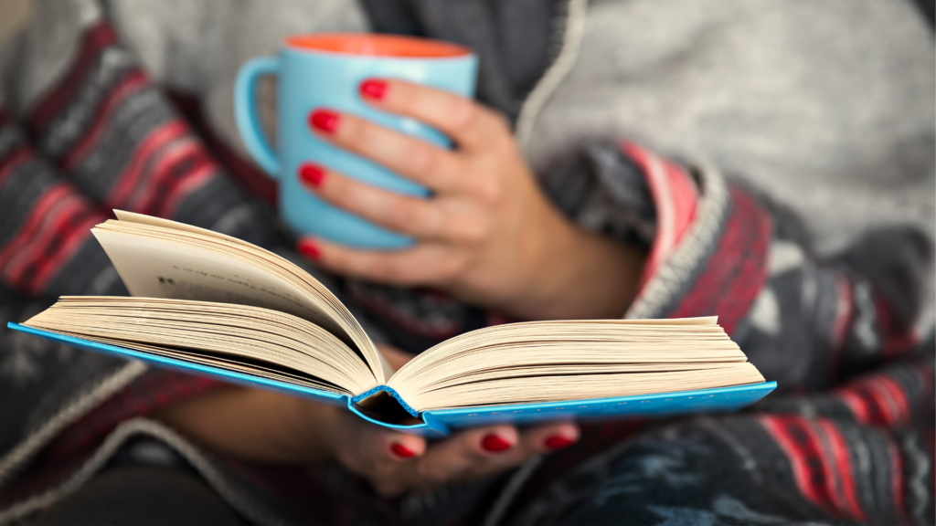 Hands holding a coffee cup and book