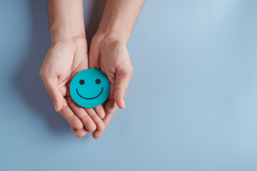 hands holding smiling emoji representing positive psychology